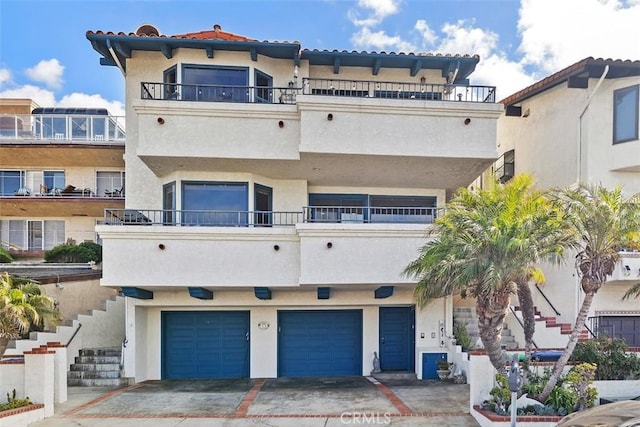 view of front facade with a balcony, an attached garage, and stucco siding