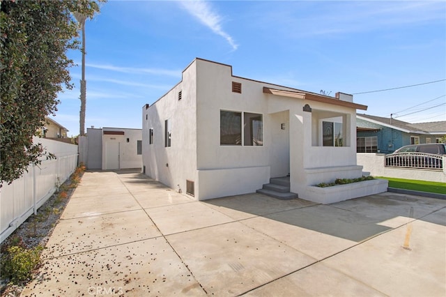 view of front facade featuring fence, a patio, and stucco siding