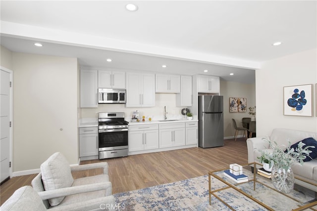 kitchen featuring light wood finished floors, stainless steel appliances, a sink, and open floor plan