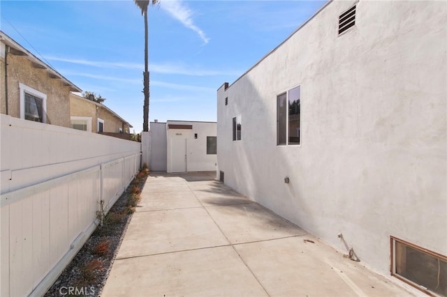 view of home's exterior with a patio area, fence, and stucco siding