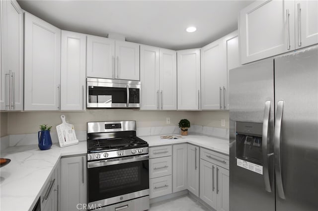 kitchen with stainless steel appliances, recessed lighting, white cabinets, and light stone countertops