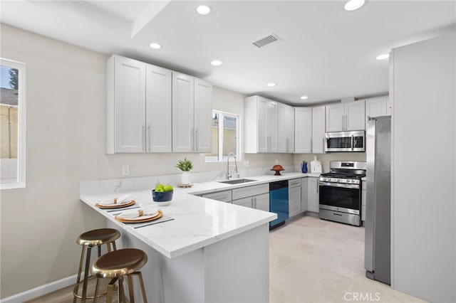 kitchen featuring recessed lighting, visible vents, appliances with stainless steel finishes, a sink, and a peninsula