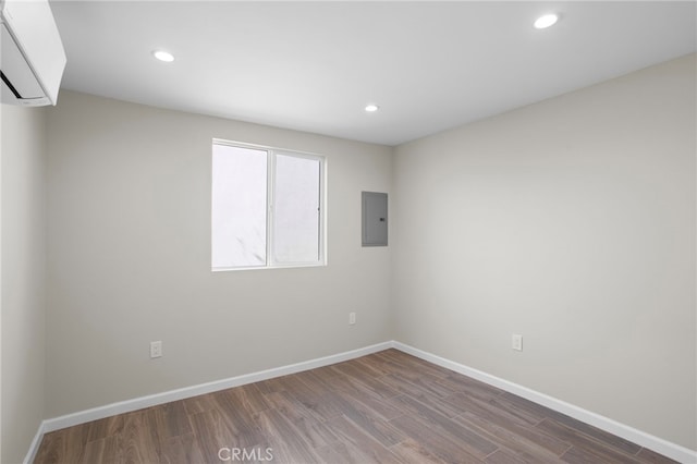 spare room featuring electric panel, baseboards, wood finished floors, and recessed lighting