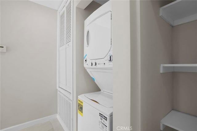 washroom with laundry area, tile patterned flooring, baseboards, and stacked washer / dryer