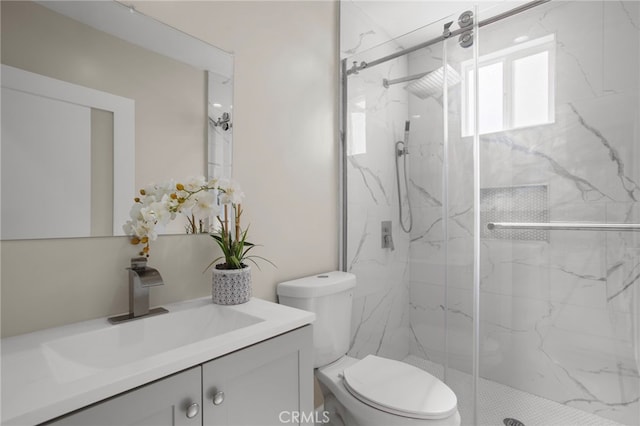 bathroom featuring toilet, a marble finish shower, and vanity