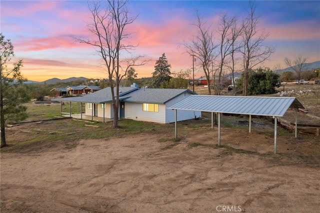 property exterior at dusk with a detached carport, a mountain view, and driveway