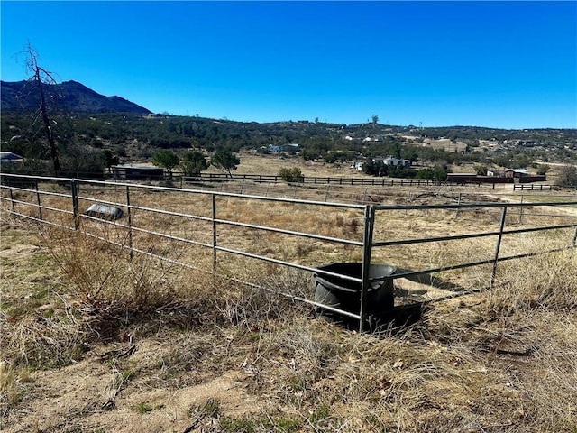 view of yard featuring fence, a mountain view, and a rural view