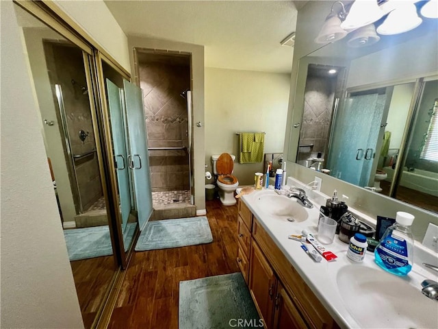 full bath featuring wood finished floors, a stall shower, a sink, and toilet