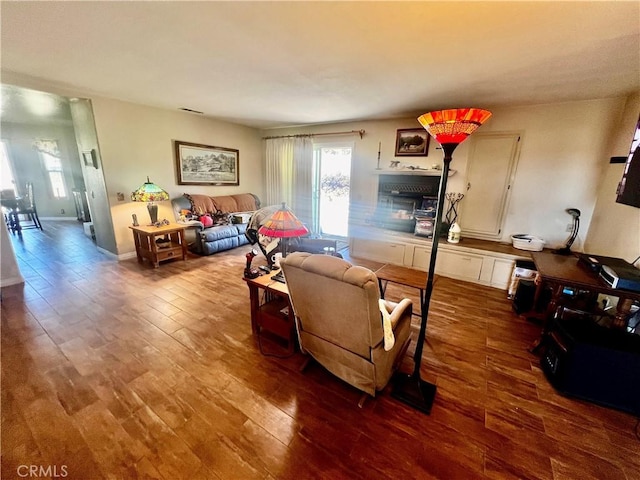 living room with baseboards, visible vents, and wood finished floors