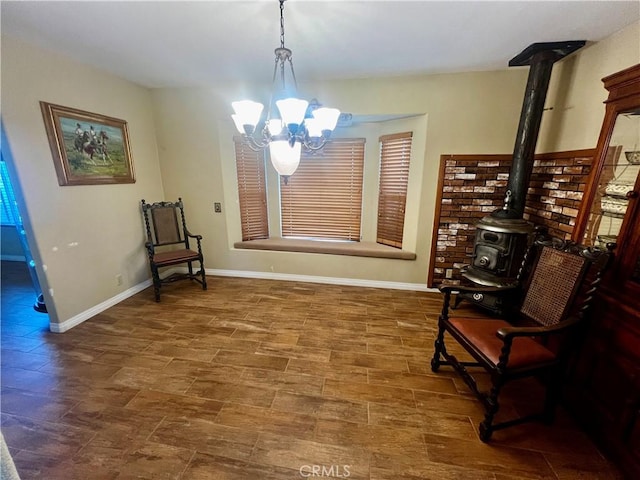 sitting room featuring a wood stove, a notable chandelier, and baseboards