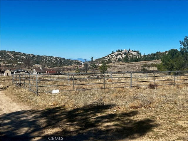 view of yard featuring a rural view, fence, and a mountain view