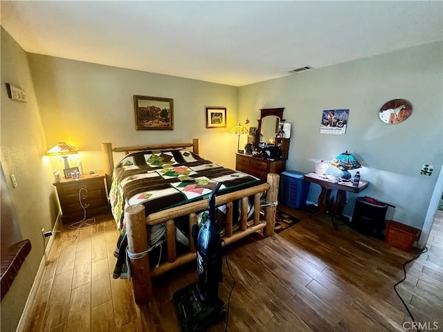 bedroom with visible vents, baseboards, and wood finished floors