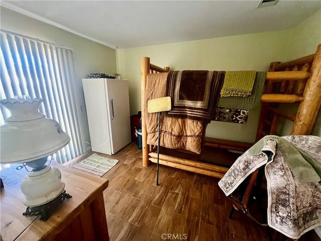 bedroom featuring wood finished floors and freestanding refrigerator