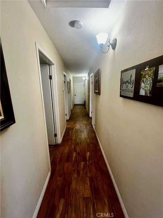 hall with baseboards and wood finished floors