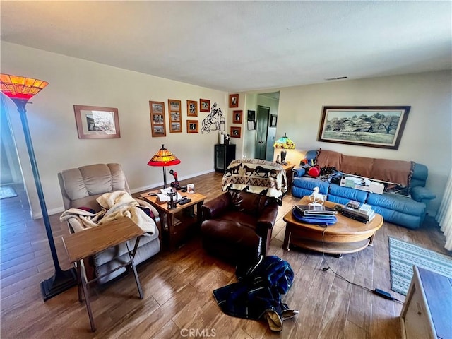 living area featuring baseboards, visible vents, and wood finished floors