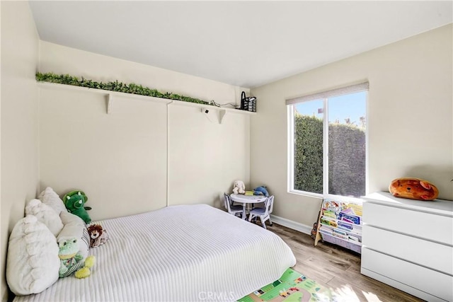 bedroom featuring light wood finished floors and baseboards