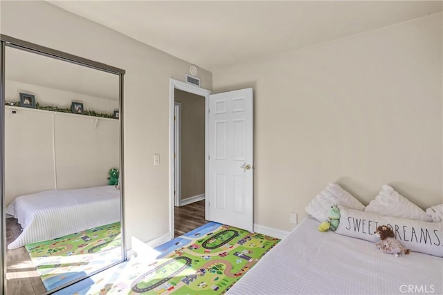 bedroom with baseboards, visible vents, a closet, and wood finished floors