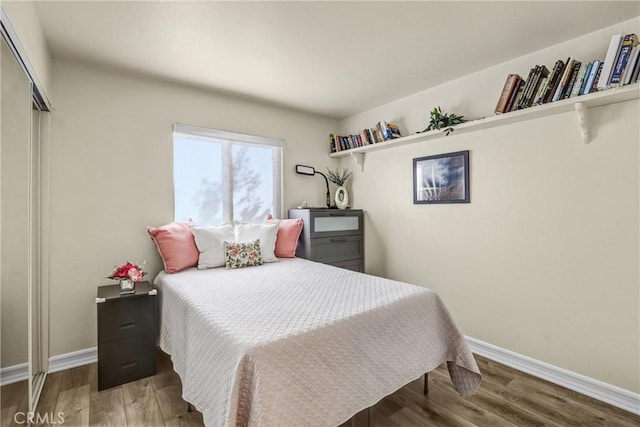 bedroom with a closet, baseboards, and wood finished floors