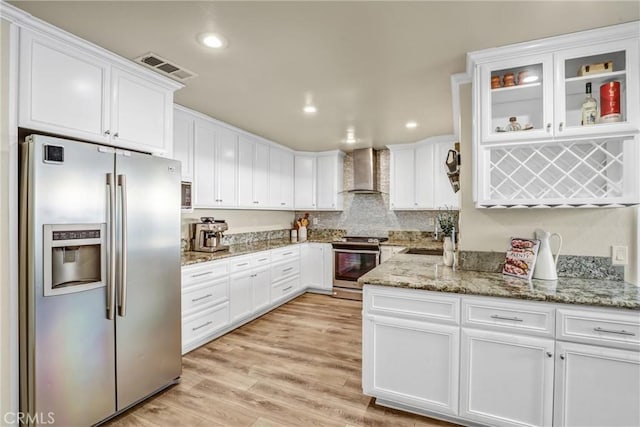 kitchen with stainless steel appliances, visible vents, light wood-style floors, white cabinetry, and wall chimney exhaust hood