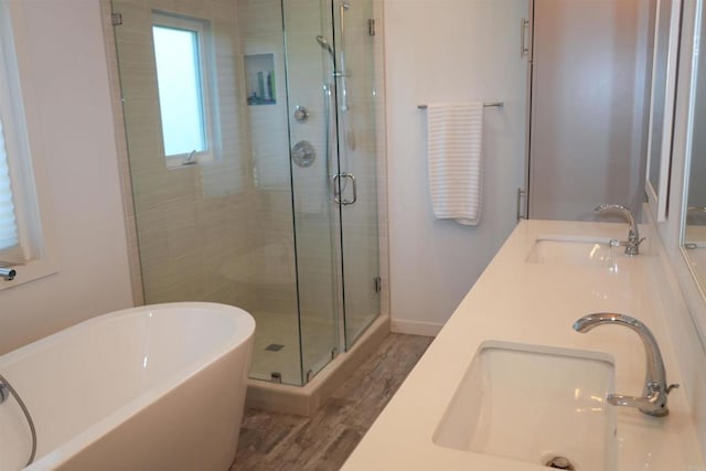 bathroom with a sink, a shower stall, a freestanding bath, and wood finished floors