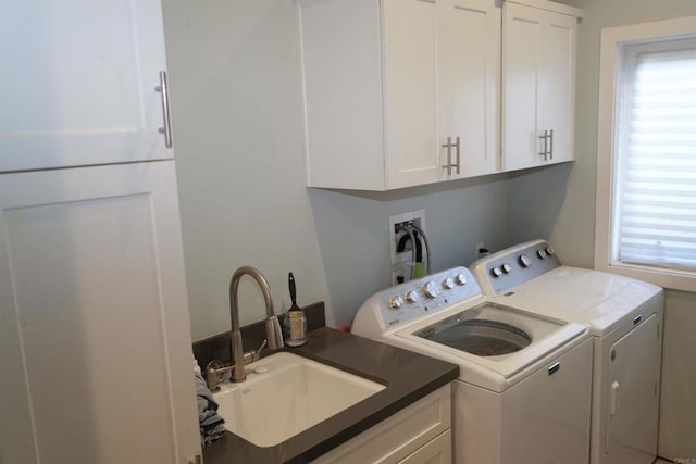 clothes washing area featuring a wealth of natural light, washer and dryer, cabinet space, and a sink