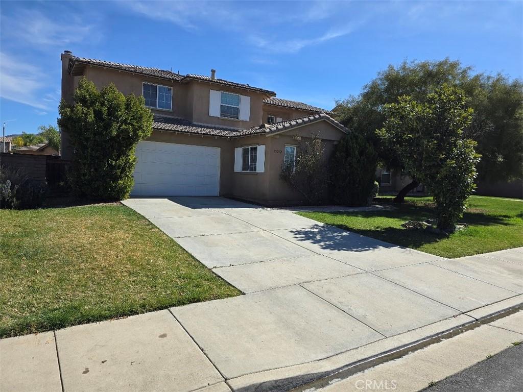 mediterranean / spanish-style house with stucco siding, concrete driveway, an attached garage, a front yard, and a tiled roof