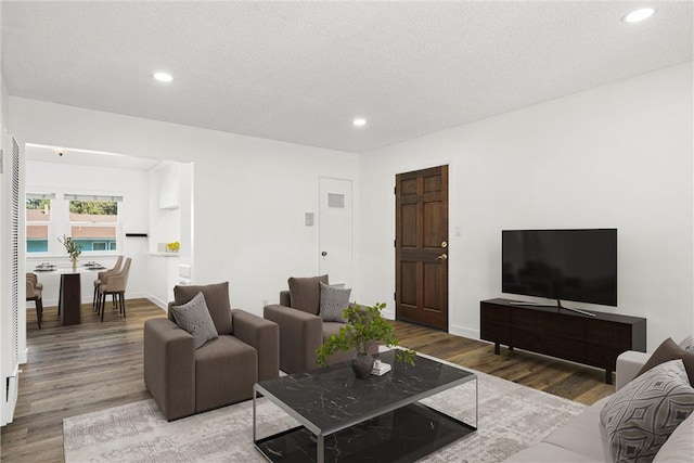 living room with a textured ceiling, baseboards, wood finished floors, and recessed lighting