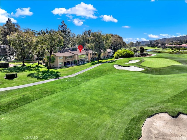 view of home's community with view of golf course and a lawn