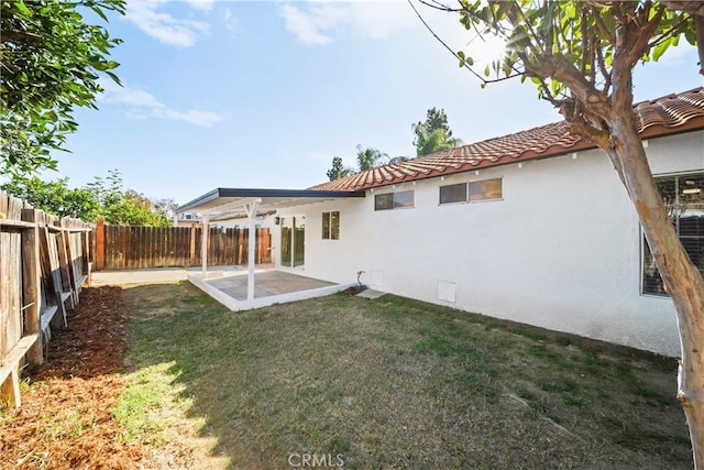 back of property featuring a tile roof, a fenced backyard, a yard, a patio area, and stucco siding