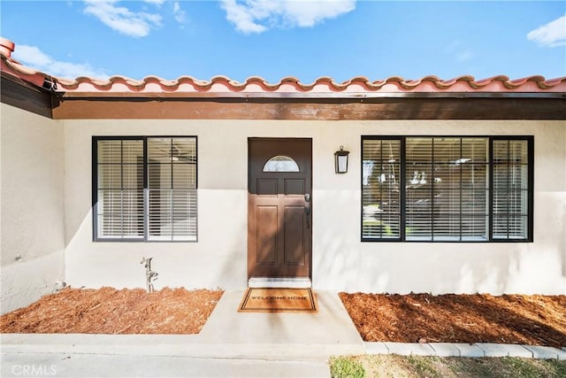 doorway to property with a tile roof and stucco siding