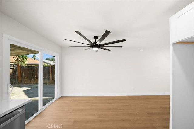 spare room featuring light wood-type flooring, a ceiling fan, and baseboards