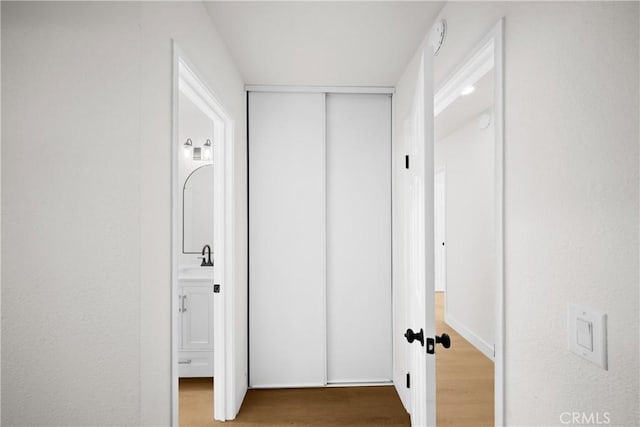 corridor with a sink and wood finished floors