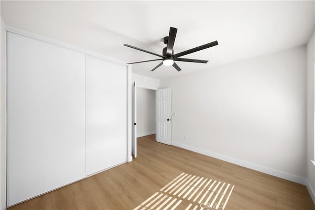 unfurnished bedroom featuring ceiling fan, a closet, wood finished floors, and baseboards