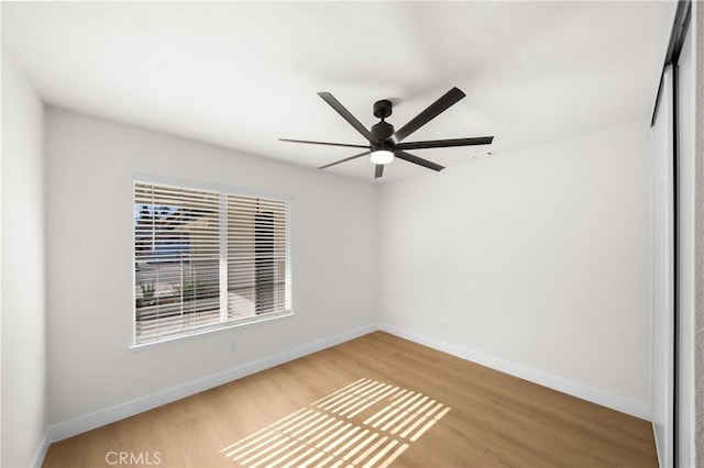 empty room with ceiling fan, wood finished floors, and baseboards