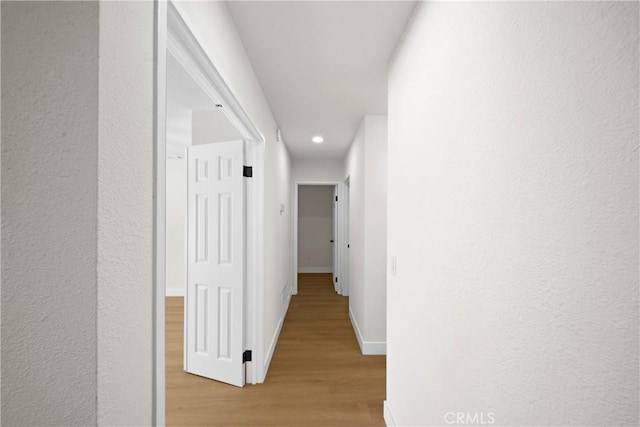 hallway with light wood finished floors and baseboards