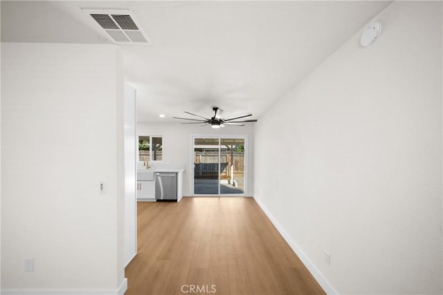 corridor with light wood-type flooring, visible vents, and baseboards