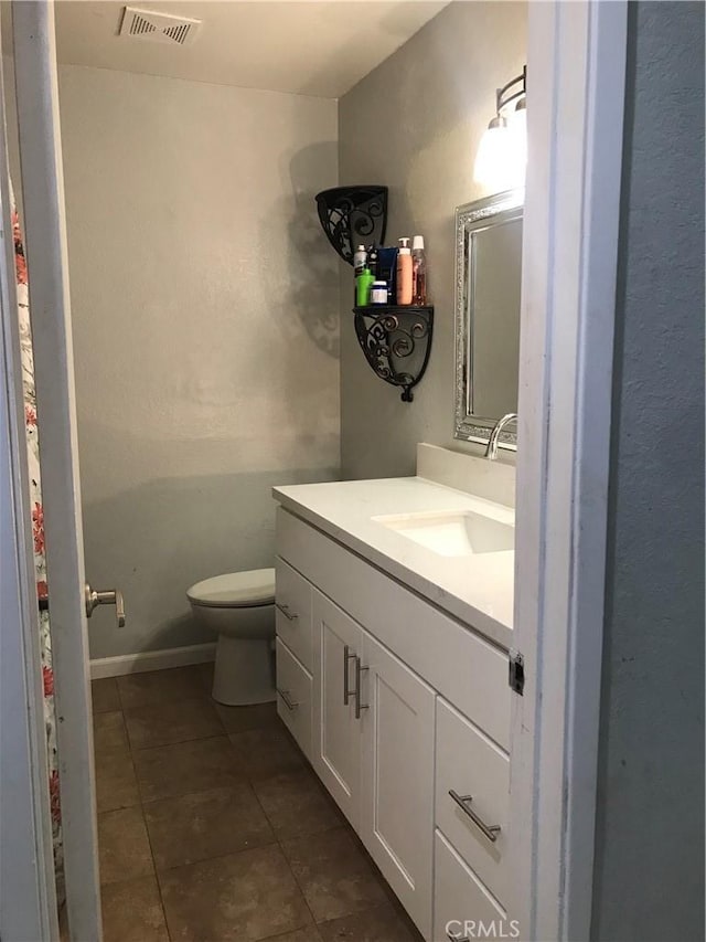 bathroom featuring visible vents, toilet, vanity, baseboards, and tile patterned floors