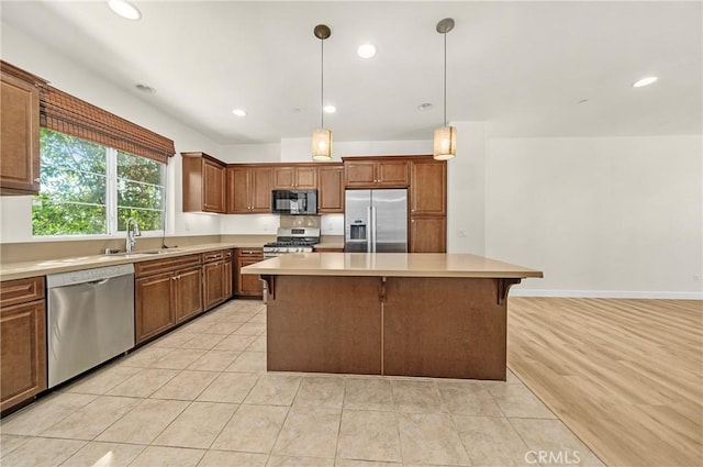 kitchen featuring stainless steel appliances, a breakfast bar, a sink, light countertops, and a center island