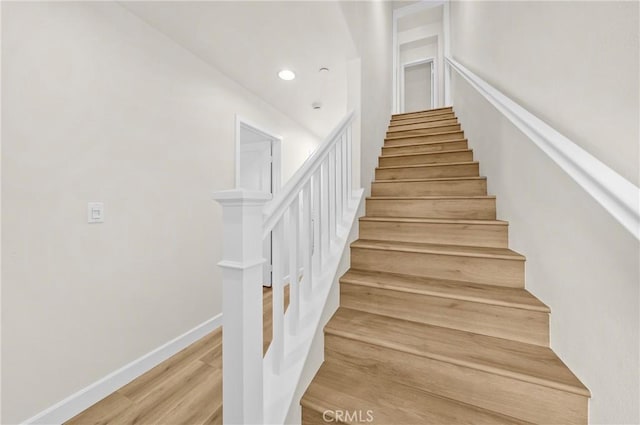 stairs with baseboards, wood finished floors, and recessed lighting