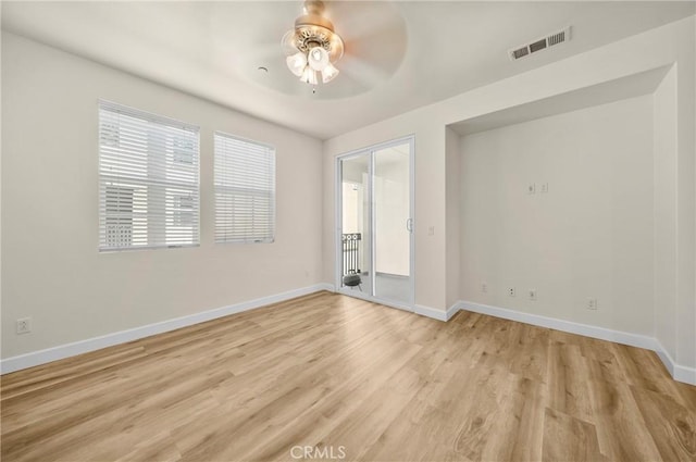 spare room with light wood finished floors, baseboards, visible vents, and ceiling fan