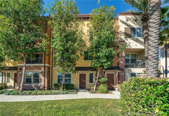 multi unit property featuring a front lawn, brick siding, and stucco siding