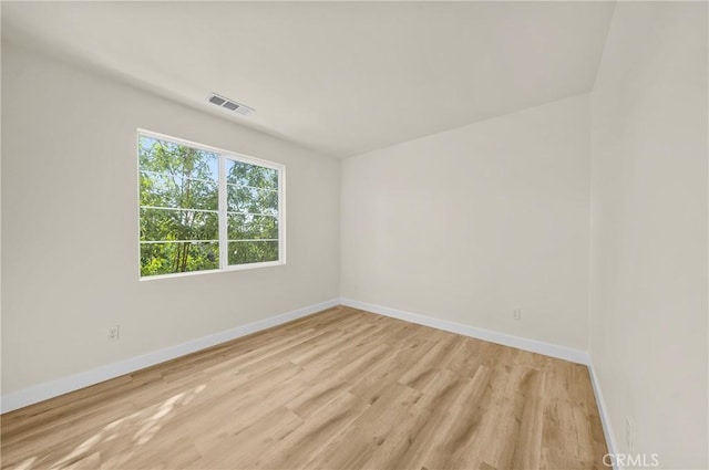 empty room featuring light wood finished floors, visible vents, and baseboards