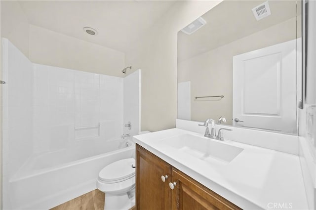 bathroom with toilet, wood finished floors, vanity, visible vents, and  shower combination