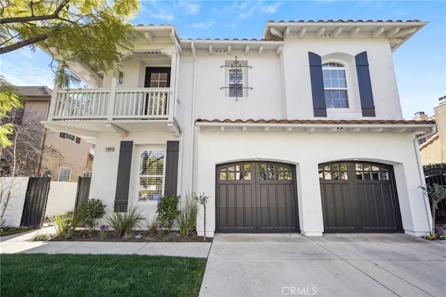 view of front of house with driveway, a garage, a balcony, fence, and stucco siding