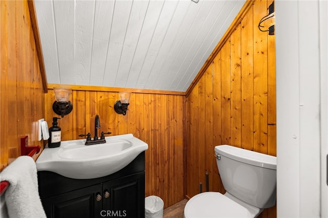 bathroom with wooden walls, toilet, lofted ceiling, wooden ceiling, and vanity