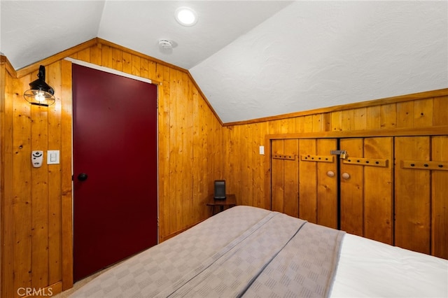 bedroom featuring a closet, lofted ceiling, and wood walls