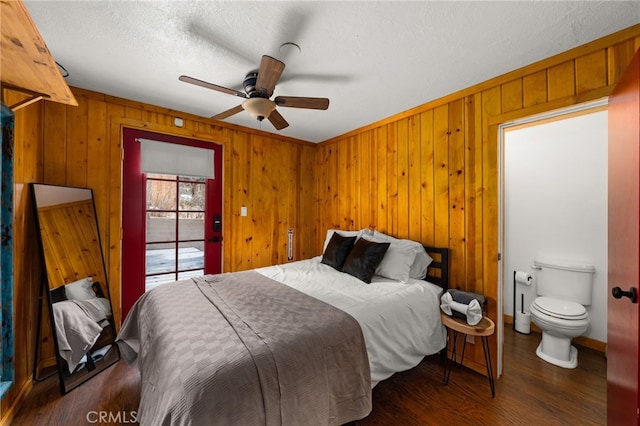 bedroom featuring a ceiling fan, a textured ceiling, wood finished floors, wood walls, and baseboards