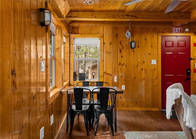 dining area featuring wooden walls, wood ceiling, baseboards, and wood finished floors