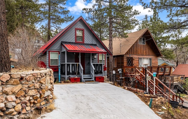 chalet / cabin with covered porch, board and batten siding, a shingled roof, and metal roof