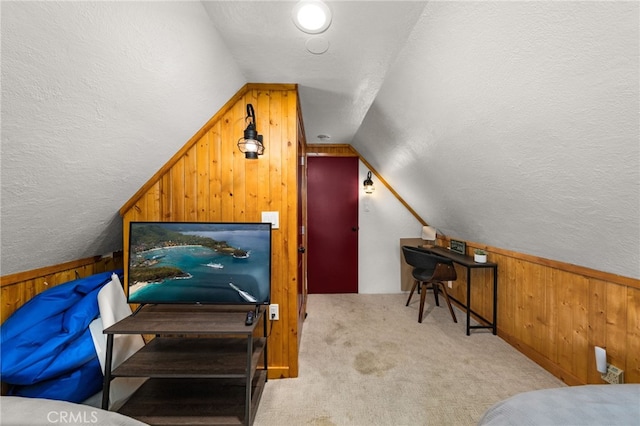 bedroom featuring lofted ceiling, wooden walls, wainscoting, and carpet